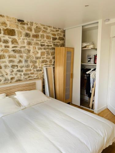 un lit dans une chambre avec un mur en pierre dans l'établissement Le cottage des remparts - face hotel de ville, à Boulogne-sur-Mer