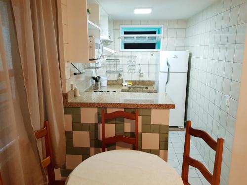 a small kitchen with a counter and a refrigerator at Apto 527 - Golden Village Taperapuã in Porto Seguro
