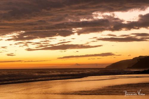a sunset on a beach with the ocean at Olas Permanentes El Zonte in El Zonte