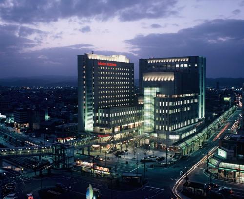 a city lit up at night with tall buildings at Takaoka Manten Hotel Ekimae in Takaoka