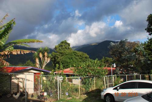 a white car parked in front of a fence with a mountain at Hostal Casa Pedro Boquete in Boquete