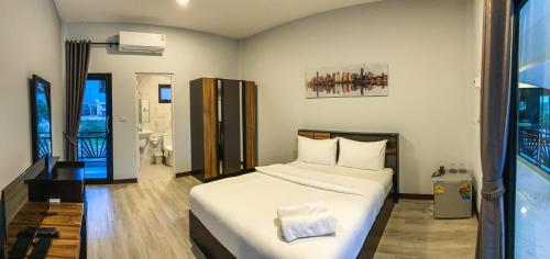 ein Schlafzimmer mit einem großen weißen Bett in einem Zimmer in der Unterkunft โรงแรมกอดหมอน in Nakhon Pathom