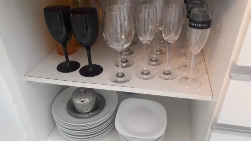 a shelf with wine glasses and plates on it at Apartamento na Riviera de São Lourenço in Riviera de São Lourenço