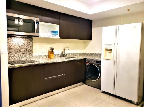 a kitchen with a white refrigerator and a dishwasher at Alameda Cariari Apartments in San José