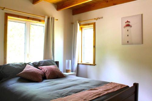 um quarto com uma cama, duas janelas e um farol em Chalet l'Authentique: Massif, Spa et Plein Air em Petite-Rivière-Saint-François