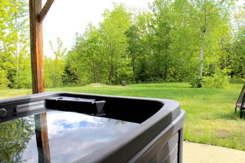 a bath tub with a view of a yard at Chalet l'Authentique: Massif, Spa et Plein Air in Petite-Rivière-Saint-François