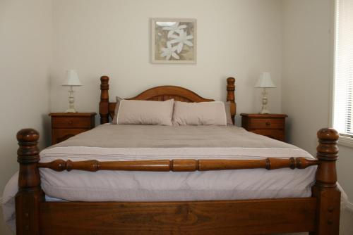 a bedroom with a wooden bed with two night stands at Breakaway Apartments in Cowra