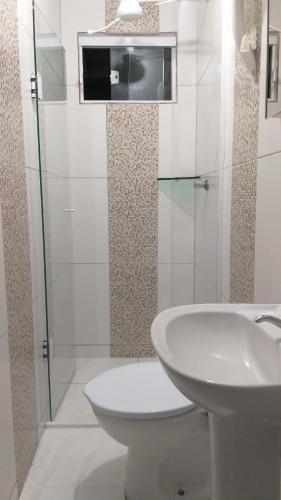 Baño blanco con lavabo y aseo en Pousada Verdes Mares guaratuba, en Guaratuba