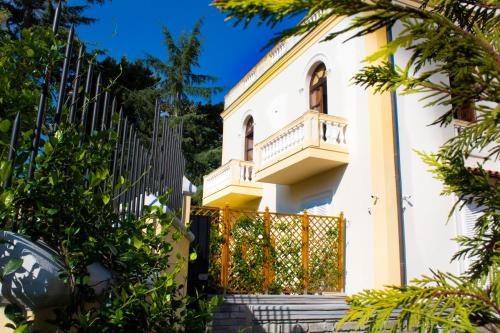 a white house with a gate and trees at Relais Villa Montedonzelli in Naples