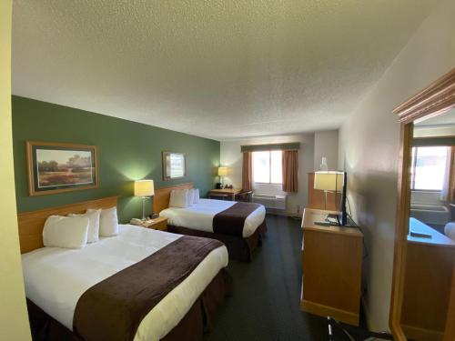 a hotel room with two beds and two windows at Baymont by Wyndham Robinson in Robinson