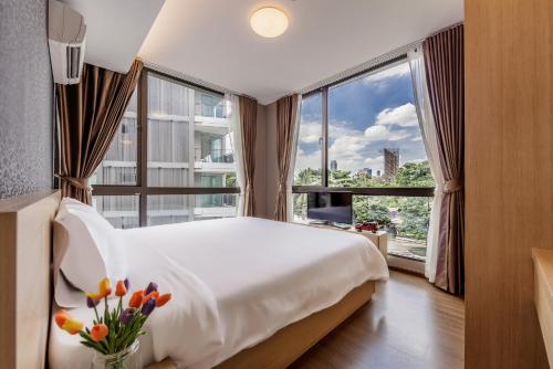 ein Schlafzimmer mit einem weißen Bett und einem großen Fenster in der Unterkunft Like Sukhumvit 22 in Bangkok