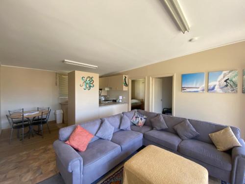a living room with a blue couch and a table at Denhams Beach Cottage in Sunshine Bay