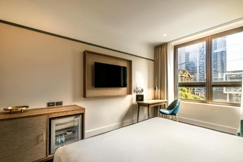 a hotel room with a television and a bed at Batman's Hill on Collins in Melbourne