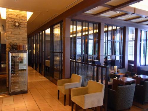 a restaurant with chairs and tables and windows at Takaoka Manten Hotel Ekimae in Takaoka