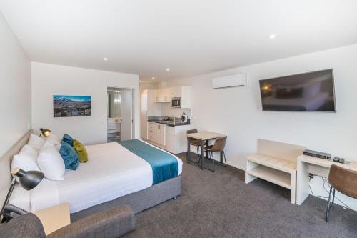 a bedroom with a bed and a desk and a kitchen at Taylors Motel in Ashburton