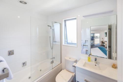 a white bathroom with a shower and a toilet at Taylors Motel in Ashburton