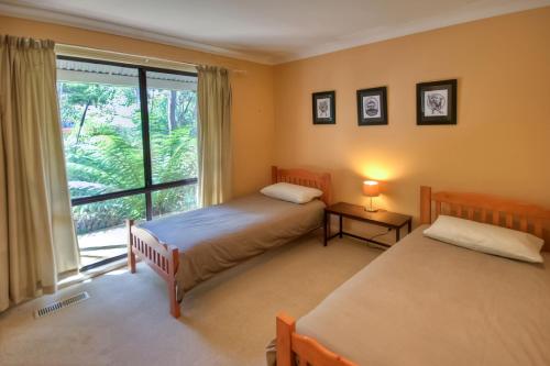 a bedroom with two beds and a large window at Camelot Cottage in Blackheath