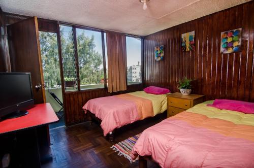 a bedroom with two beds and a television at Arequipay Backpackers Downtown in Arequipa