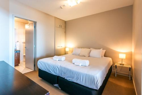 a bedroom with a large bed with two pillows on it at Sanctuary On The Beach - Onetangi by Waiheke Unlimited in Onetangi