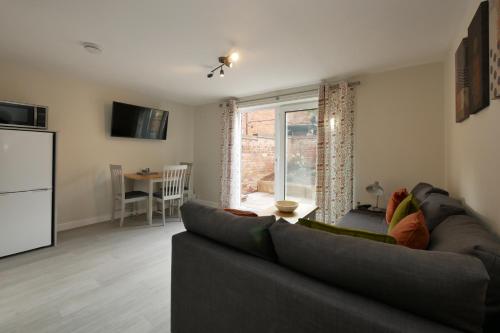 a living room with a gray couch and a kitchen at Crewe Short Lets 8 Victoria Court, Crewe in Crewe