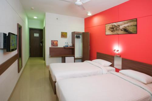 a room with three beds and a red wall at Ginger Nashik in Nashik