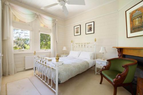 a bedroom with a white bed and a green chair at Heathmont in Blackheath