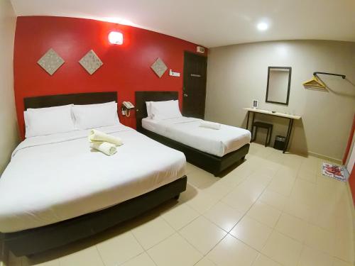 a hotel room with two beds and a red wall at JV Hotel @ Simpang Ampat in Simpang Ampat