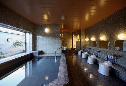 a bathroom with a tub and a row of sinks at Tsuruga Manten Hotel Ekimae in Tsuruga