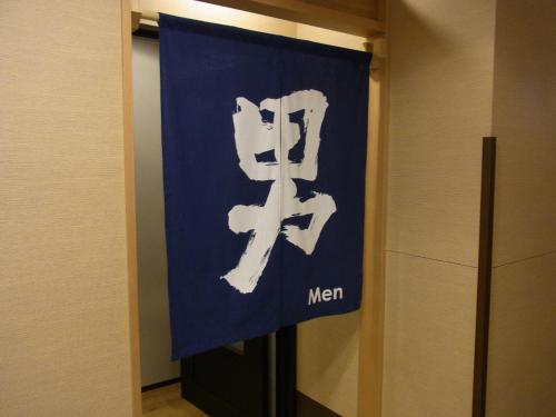a blue and white sign with the word men at Tsuruga Manten Hotel Ekimae in Tsuruga