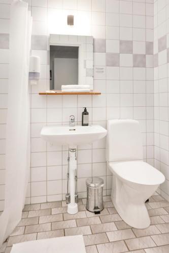 a white bathroom with a toilet and a sink at Hotell Vesterhavet in Falkenberg