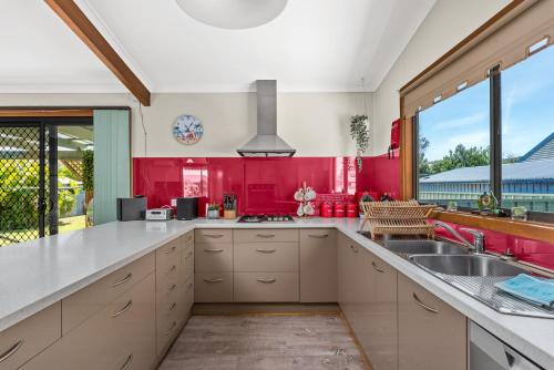 a kitchen with red walls and a large window at Footprints in the Sand, Silver Sands Beach House in Aldinga Beach