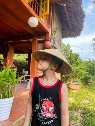 a young boy wearing a straw hat with a pipe at Pài Bjooc homestay in Làng Mán