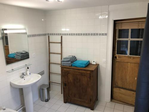 La salle de bains est pourvue d'un lavabo et d'un miroir. dans l'établissement Gîte de charme à la campagne, à Troarn