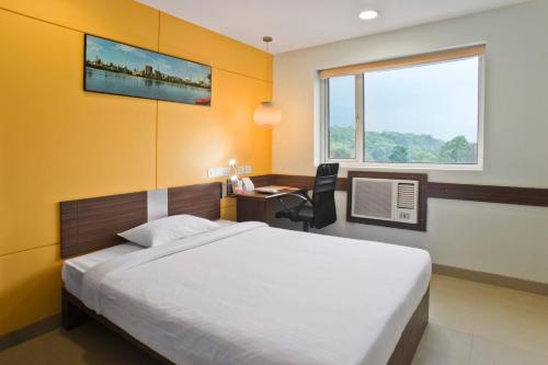 a bedroom with a bed and a desk and a window at Ginger Guwahati in Guwahati