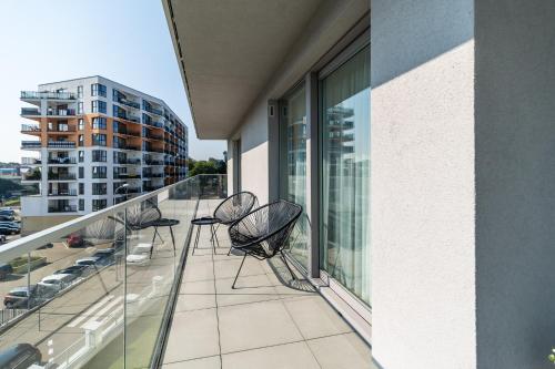 eine Reihe von Stühlen auf dem Balkon eines Gebäudes in der Unterkunft Stylish Apartment Balticus 15 with Air Conditioning by Noclegi Renters in Misdroy