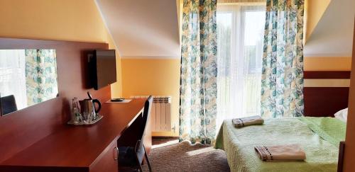 um quarto com uma cama, uma secretária e uma janela em Pensjonat Sielanka em Solec-Zdrój