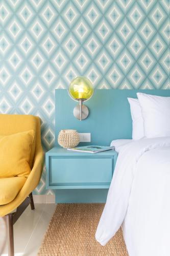 a bedroom with a blue bed and a yellow chair at MAMAKA by Ovolo in Kuta
