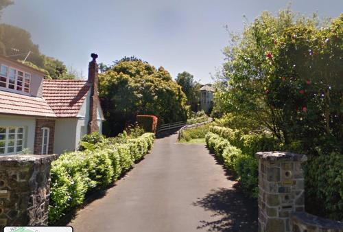una strada che conduce a una casa con cespugli e alberi di 25 Glenfell Place - One Bedroom Studio ad Auckland