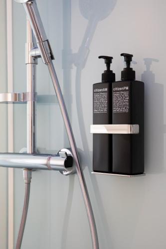 two bottles ofodorizers sitting on a shelf in a bathroom at citizenM Geneva in Geneva