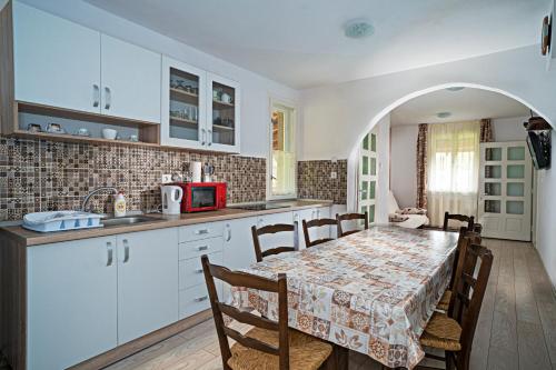 una cucina con tavolo e sedie e una cucina con armadietti bianchi di Anna Guesthouse a Lunca de Sus