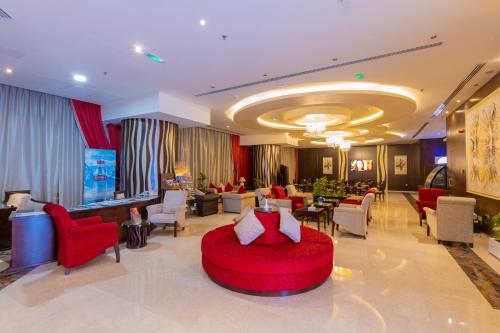 a hotel lobby with a red couch and chairs at Ewan Ajman Suites Hotel in Ajman 