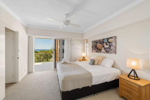 a white bedroom with a bed and a balcony at Ocean View 3 bedroom Apartment in Mudjimba