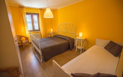 a yellow room with two beds and a couch at Serena Charme View in Mezzolago