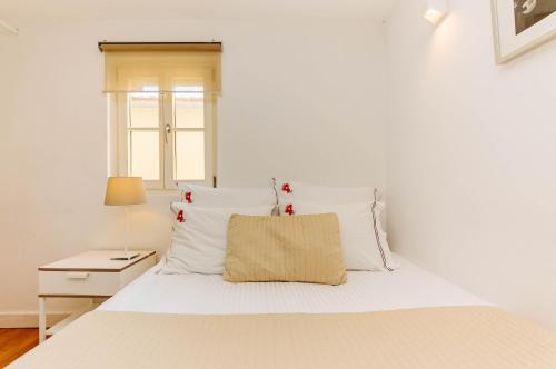 - une chambre blanche avec un lit et des oreillers blancs dans l'établissement Rent4Rest Bairro Alto Charming 1Bd Apartment, à Lisbonne