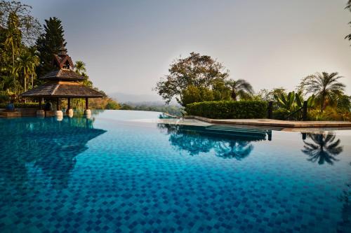 金三角的住宿－Anantara Golden Triangle Elephant Camp & Resort，一个带凉亭和蓝色海水的游泳池