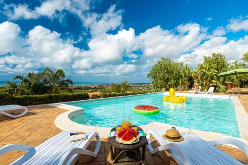 una piscina con due sedie e uno scivolo d'acqua di Solemar Sicilia - Le Casette Di Calzata a Campofelice di Roccella