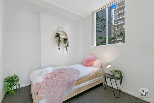 um quarto branco com uma cama com um cobertor rosa em WARRICK FRAM 3 BEDS APT FREE PARKING WALK TO WESTFIELD CLOSE TO HOSPITAL NWF003 em Warwick Farm