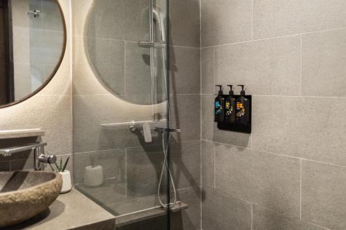 a bathroom with a shower with a sink and a mirror at MAMAKA by Ovolo in Kuta