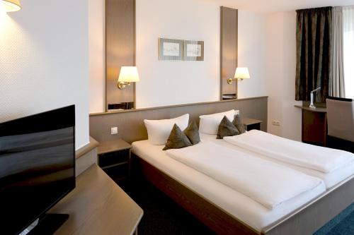 a hotel room with a bed and a flat screen tv at Hotel am Wasserfall in Lingen