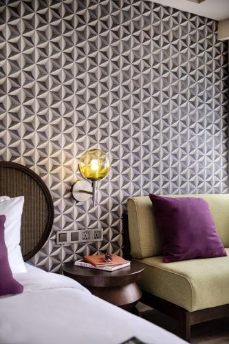 a bedroom with a bed and a chair and a wall at MAMAKA by Ovolo in Kuta